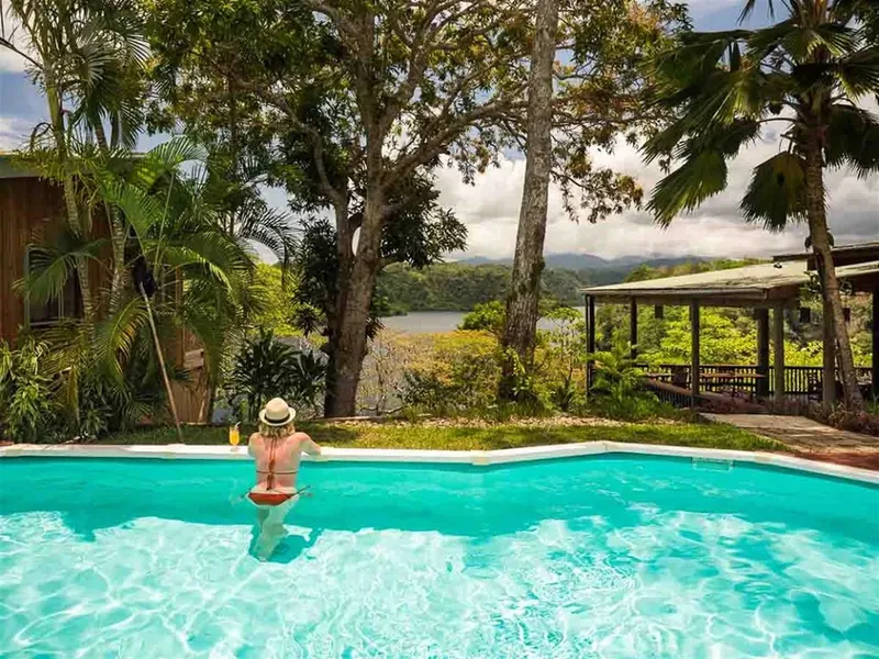 Femme dans une piscine avec vue sur la mer et végétation tropicale