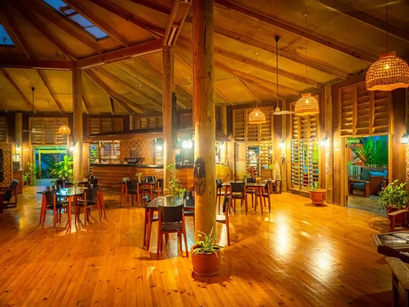 Grande salle ouverte en bois avec tables, chaises et éclairage chaleureux