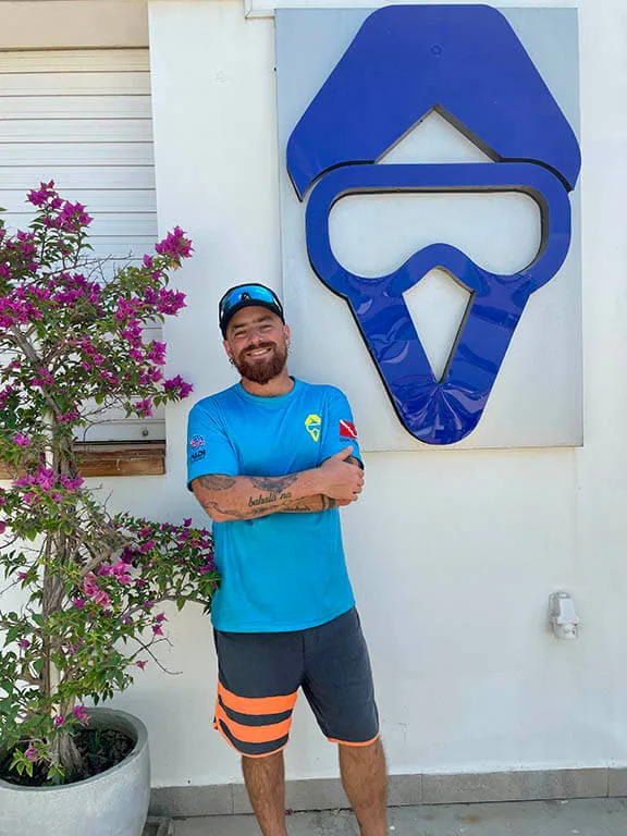 Un homme souriant devant un mur avec un masque de plongée