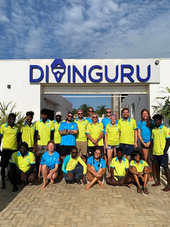 Groupe de personnes souriantes devant le centre de plongée DIVINGURU