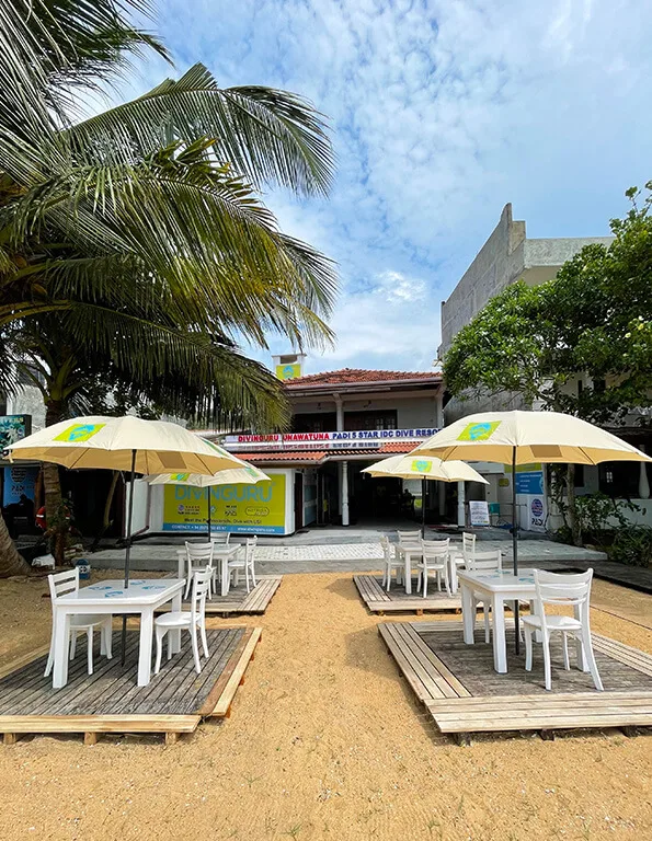 Terrasse ombragée avec tables et chaises devant un bâtiment coloré