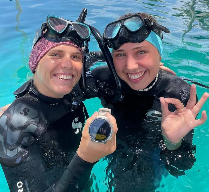 Deux plongeuses souriantes en combinaison, masque et ordinateur de plongée