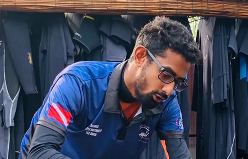 Un homme portant des lunettes et un polo bleu manipule un objet
