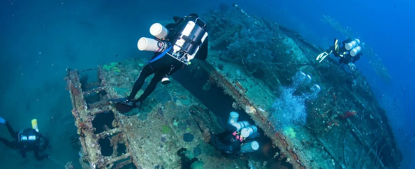 Plongeurs explorant l'épave d'un navire, lumière bleue, visibilité claire