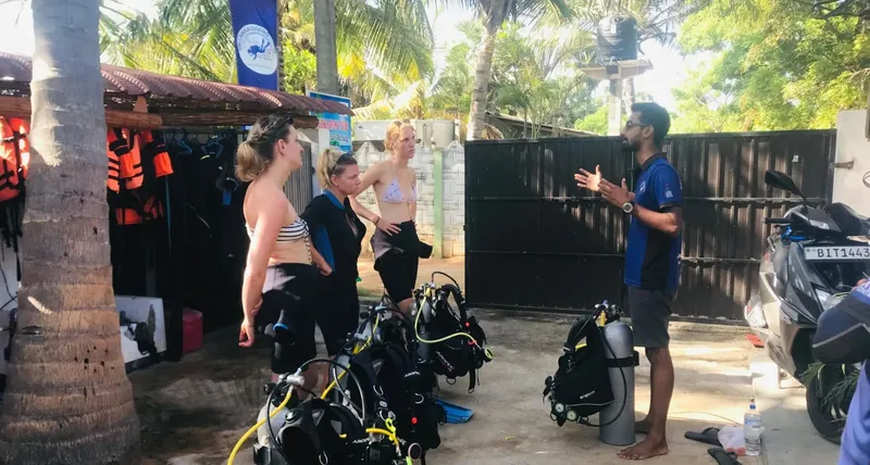 Plongeurs écoutent un instructeur près de l'équipement et d'un scooter