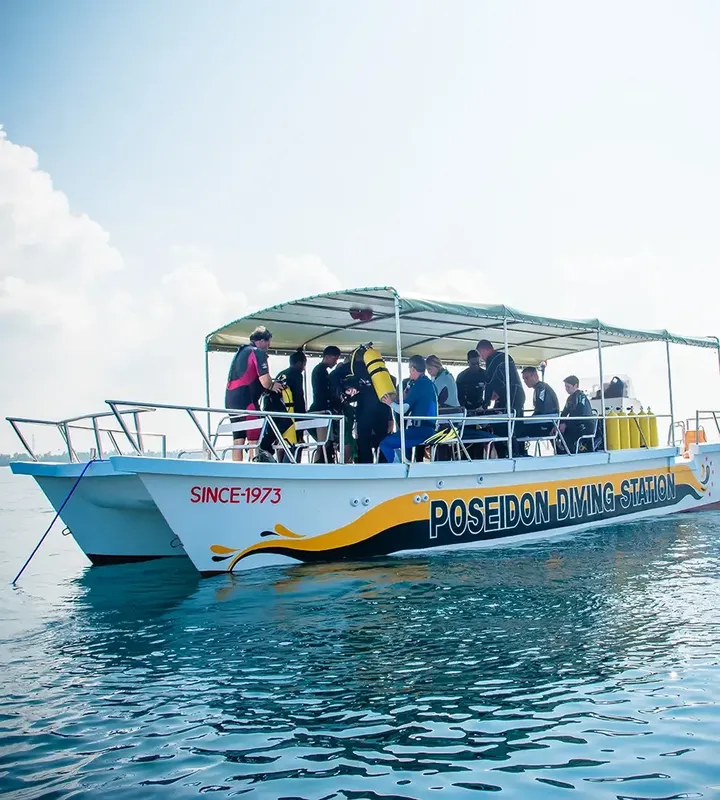 Bateau de plongée blanc avec des plongeurs et l'inscription Poseidon