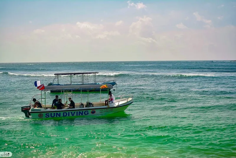 Bateau de plongée vert et bleu navigue sur une mer agitée