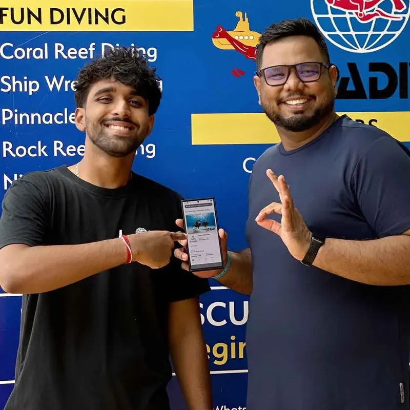 Deux hommes souriants présentent un smartphone avec une image sous-marine