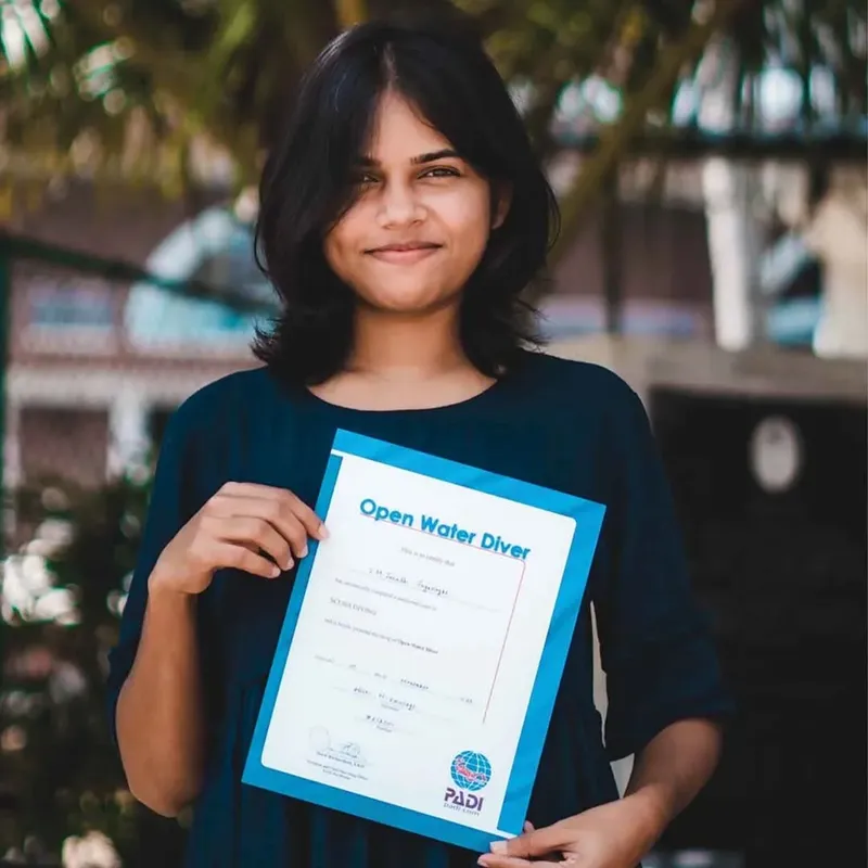Jeune femme souriante tenant un certificat de plongee Open Water Diver