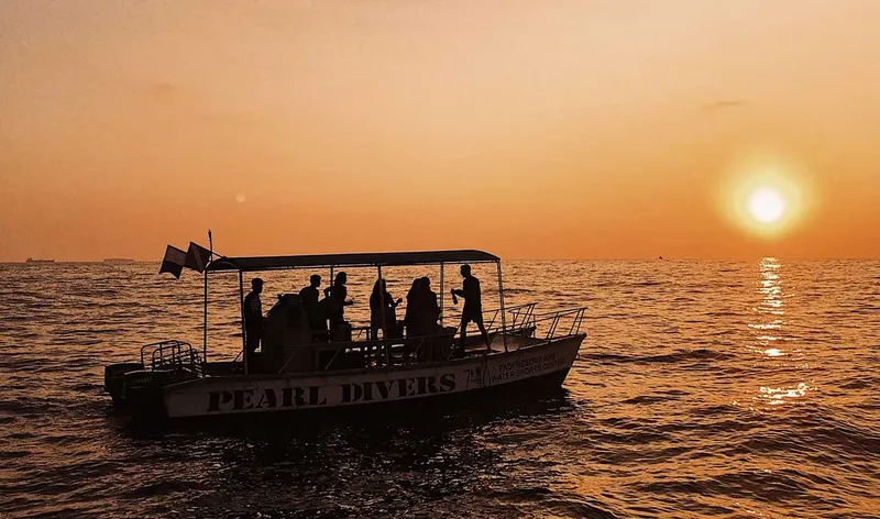 Bateau de plongee avec des personnes à bord au coucher du soleil