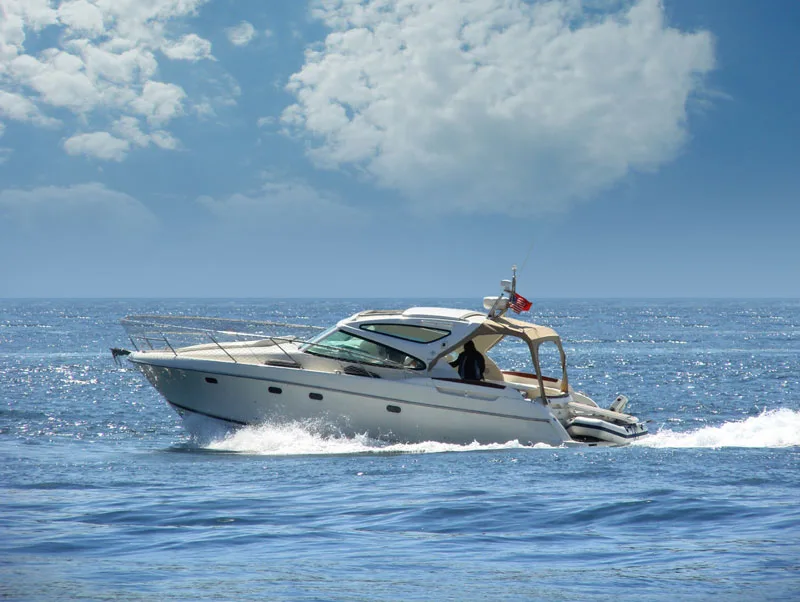 Bateau à moteur blanc navigue sur une mer bleue sous un ciel nuageux