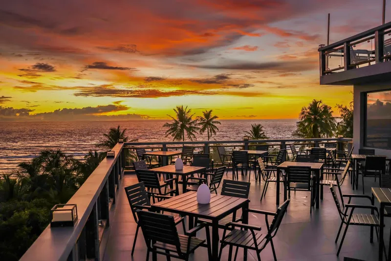 Terrasse avec tables et chaises face à la mer au coucher du soleil