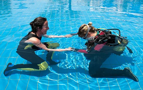 Deux femmes en combinaison de plongée s'entraînent dans une piscine