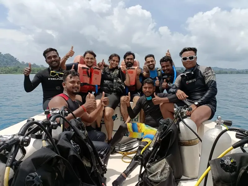 Groupe de plongeurs souriants sur un bateau en mer, pouces levés