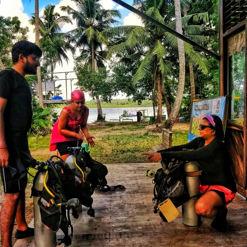 Trois plongeurs équipés discutent près d'un centre de plongée tropical