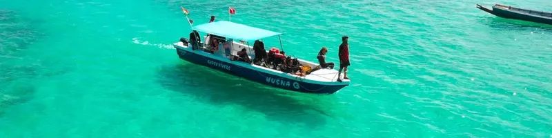 Bateau de plongée bleu avec des passagers sur une eau turquoise
