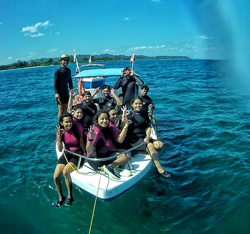 Groupe de plongeurs souriants à bord d'un bateau en mer