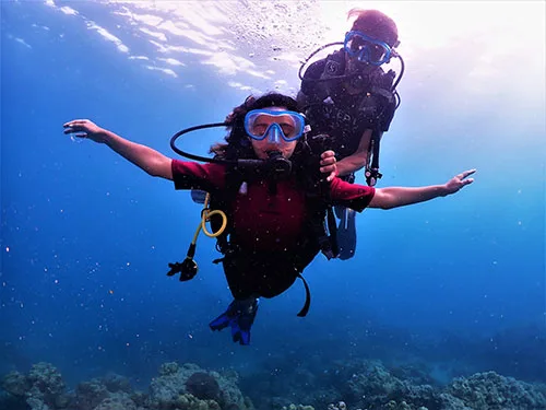 Deux plongeurs sourient et flottent dans l'eau bleue claire
