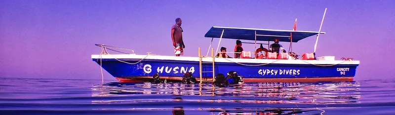 Bateau de plongée bleu avec des plongeurs et du matériel à bord