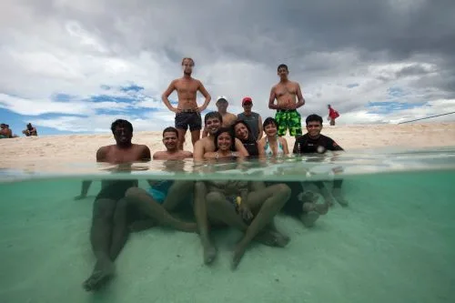 Groupe de personnes souriantes dans l'eau turquoise, moitié immergées