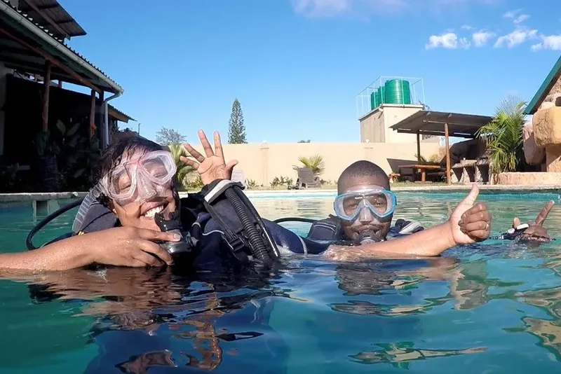 Deux plongeurs souriants avec leur équipement dans une piscine