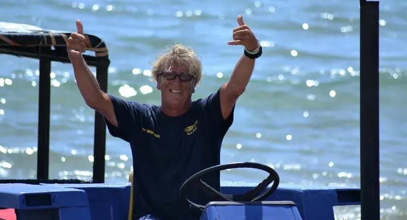 Homme souriant fait un signe de pouce levé sur un bateau