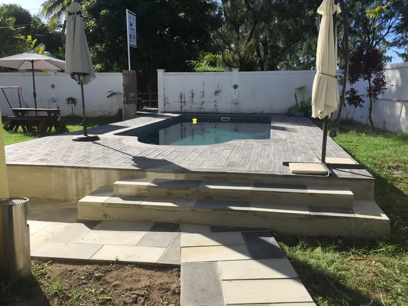 Petite piscine rectangulaire entourée d'une terrasse en bois et de végétation
