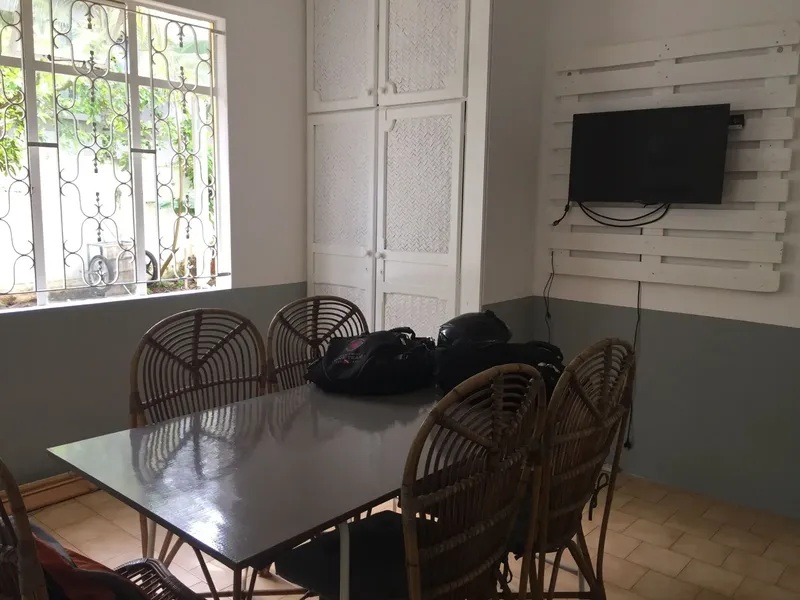 Salle de repos avec table, chaises, sacs et télévision murale