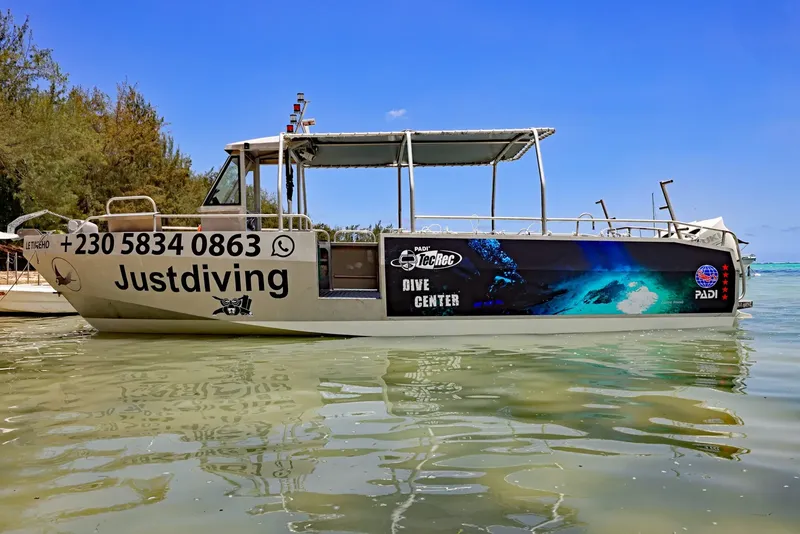 Bateau de plongée amarré avec le nom du centre et logos PADI