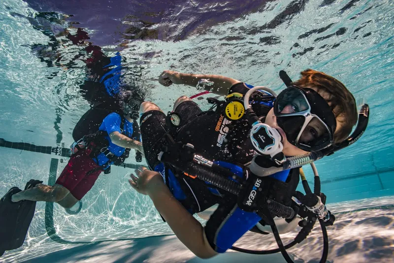 Deux plongeurs en formation, équipés, évoluent dans une piscine