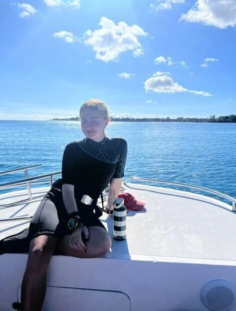 Plongeuse assise sur la proue d'un bateau en mer