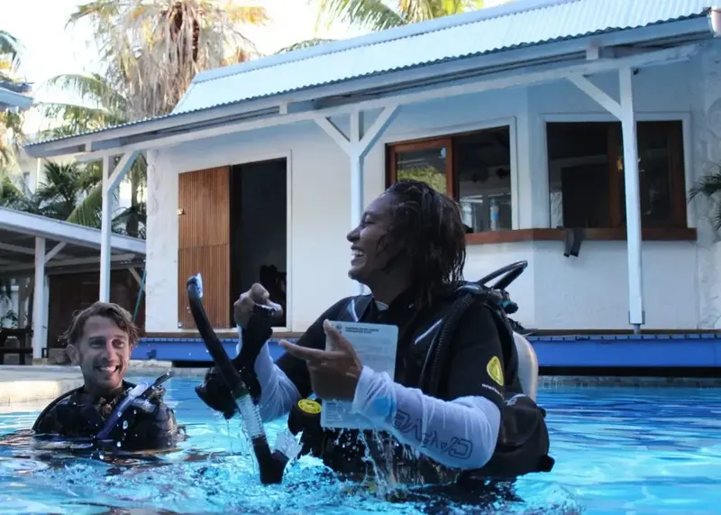 Deux plongeurs souriants dans une piscine avec du matériel de plongée
