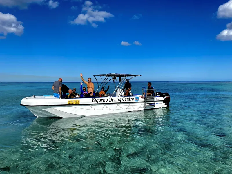 Bateau de plongée avec des passagers souriants sur une eau turquoise claire