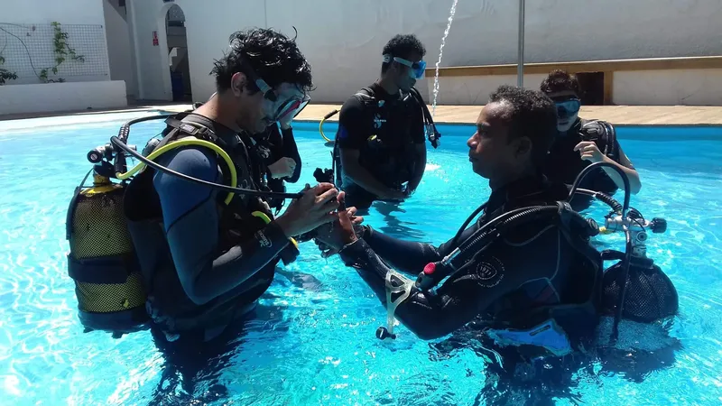 Trois plongeurs en formation dans une piscine, vérification du matériel