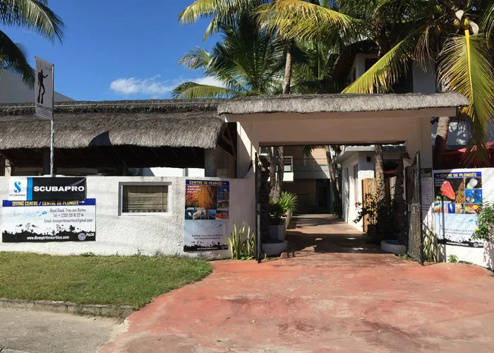 Entree d'un centre de plongee avec panneaux et vegetation tropicale