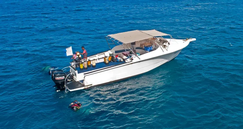 Bateau de plongée blanc avec des bouteilles et un plongeur en préparation