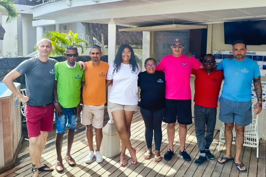 Groupe de personnes souriantes posant devant un bâtiment avec un ponton