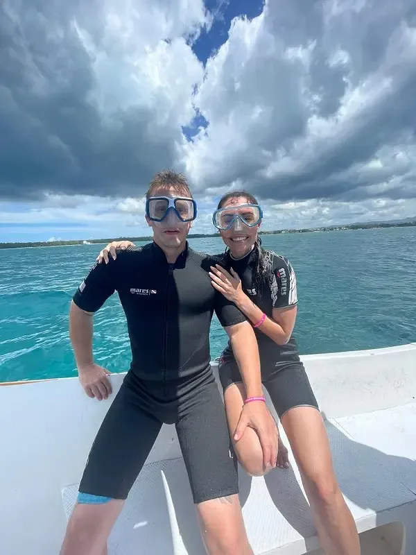 Deux plongeurs souriants en combinaison sur un bateau en mer