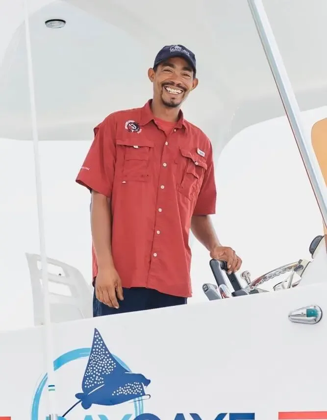 Homme souriant sur un bateau de plongée, portant une casquette et une chemise
