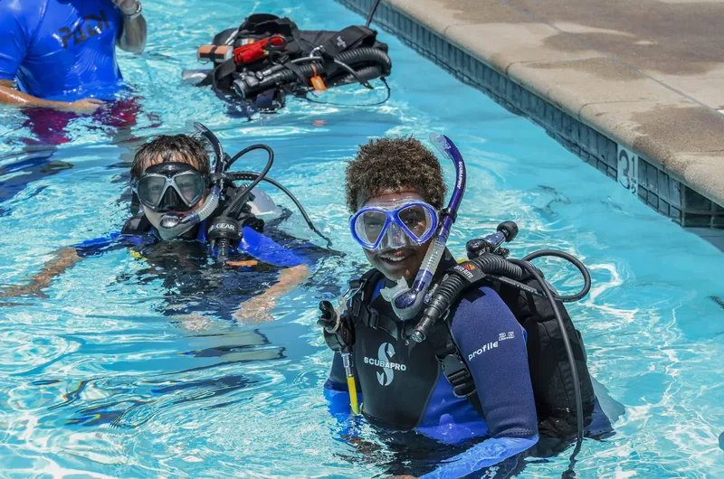 Deux plongeurs souriants en formation dans une piscine bleue