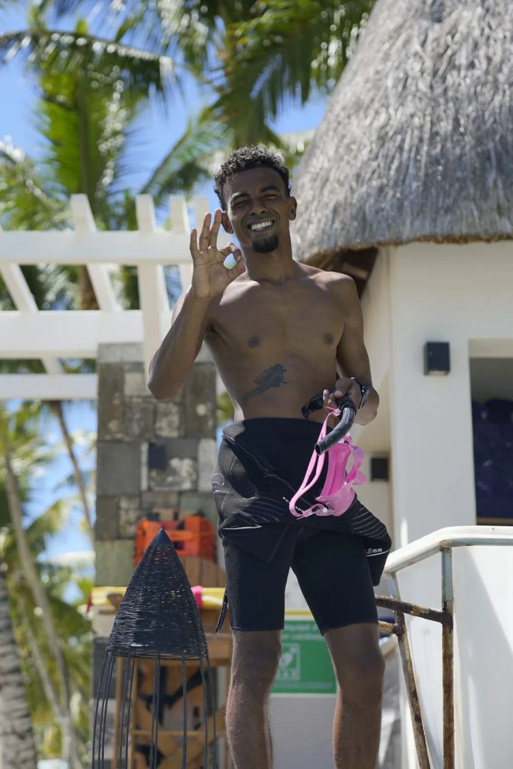 Plongeur souriant sur un ponton avec du matériel de plongée