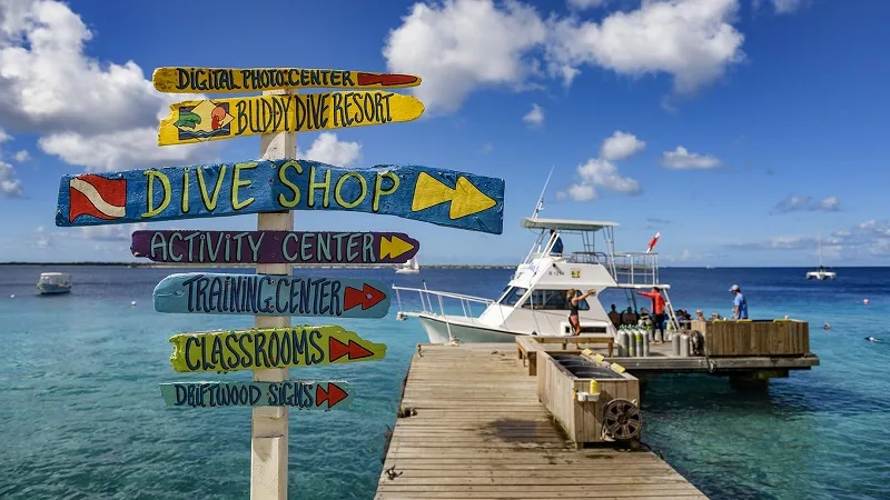 Panneau indicateur coloré, bateau de plongée amarré au ponton, mer turquoise