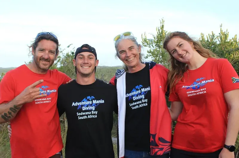 Quatre personnes souriantes posent devant un fond de végétation floue