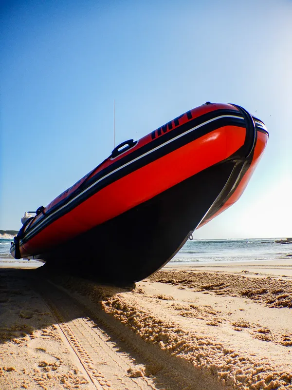 Bateau pneumatique rouge et noir échoué sur une plage de sable