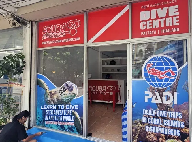 Façade d'un centre de plongée avec affiches et une personne