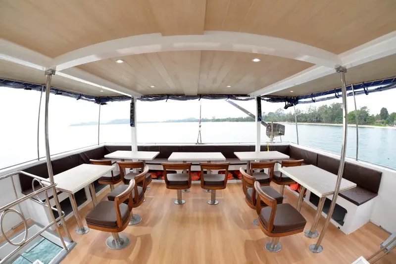 Intérieur d'un bateau de plongée avec tables et sièges face à la mer