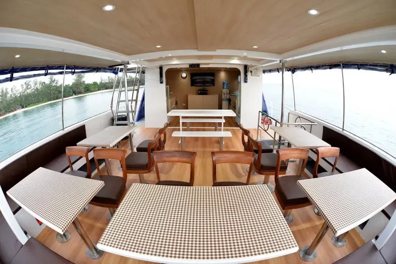 Intérieur d'un bateau de plongée avec tables, chaises et un écran