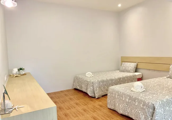 Chambre avec deux lits simples, bureau et décoration minimaliste claire