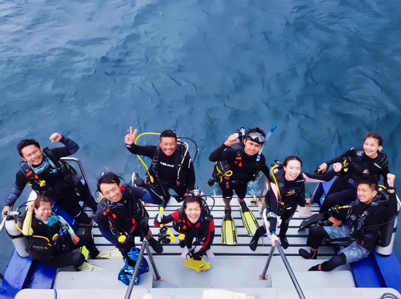 Groupe de plongeurs souriants sur le pont d'un bateau en mer