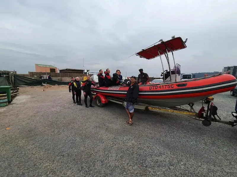 Groupe de plongeurs près d'un bateau rouge sur remorque